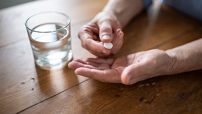 В руке лежит белая таблетка